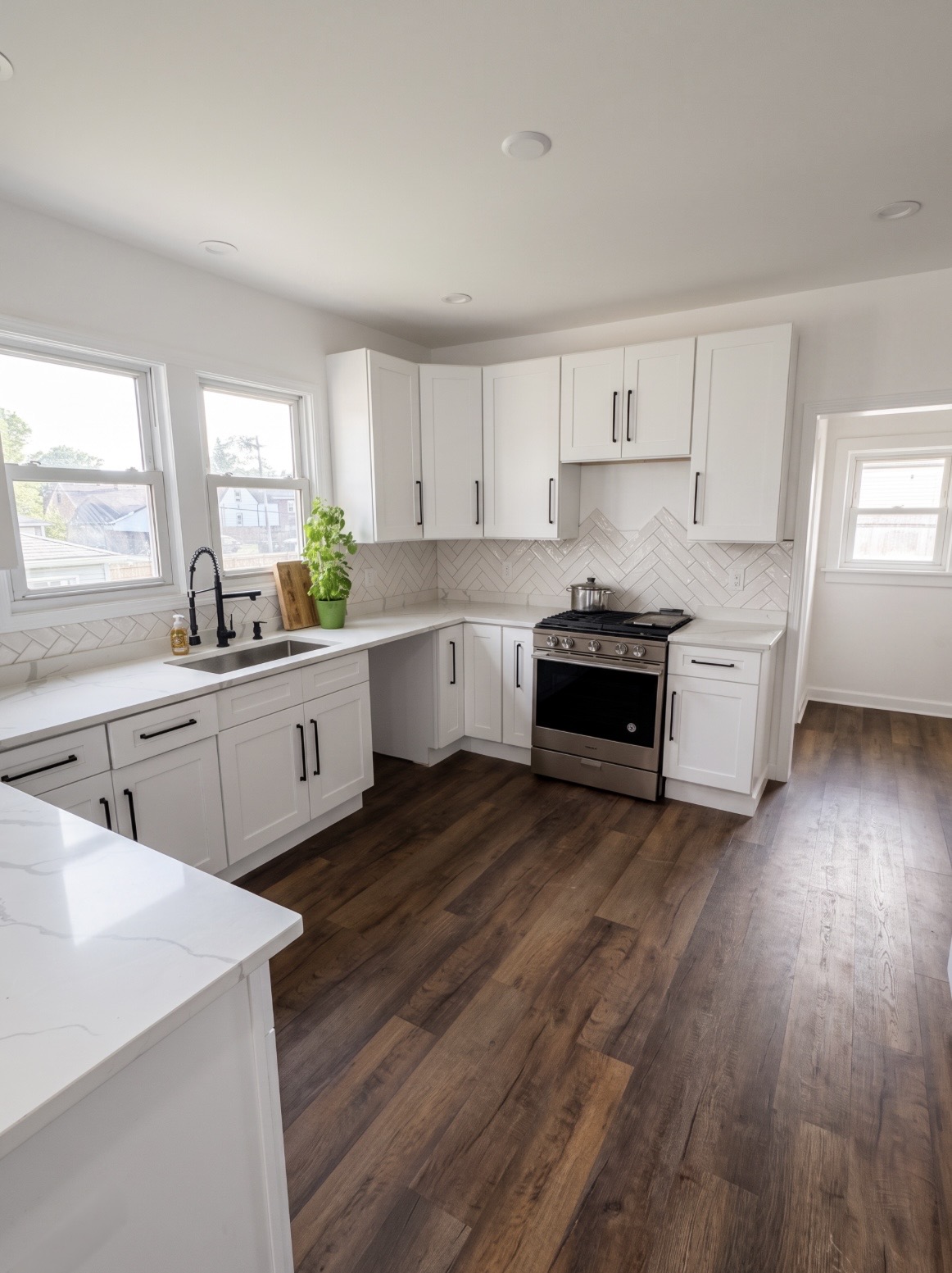 Remodeled kitchen with white shaker cabinets, quartz counters and vinyl plank flooring
